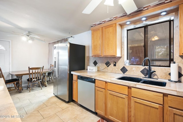 kitchen with sink, ceiling fan, appliances with stainless steel finishes, light tile patterned flooring, and decorative backsplash