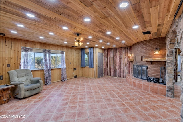 unfurnished living room featuring ceiling fan, wood walls, wood ceiling, and a fireplace