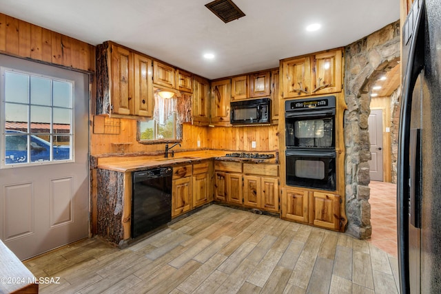 kitchen featuring black appliances, light hardwood / wood-style floors, and sink