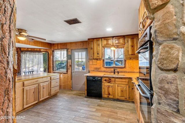 kitchen featuring ceiling fan, sink, black appliances, and wooden walls