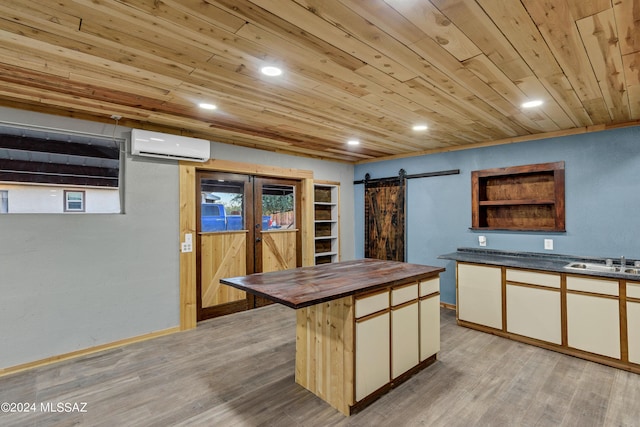 kitchen with wooden counters, wood ceiling, a wall mounted AC, a barn door, and light hardwood / wood-style floors