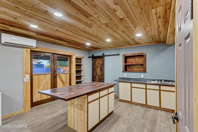 kitchen with a center island, light hardwood / wood-style flooring, a barn door, butcher block counters, and a wall unit AC