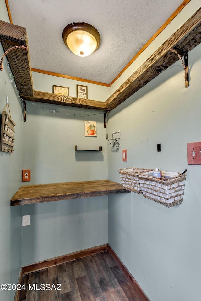 interior space with a textured ceiling, ornamental molding, and dark wood-type flooring