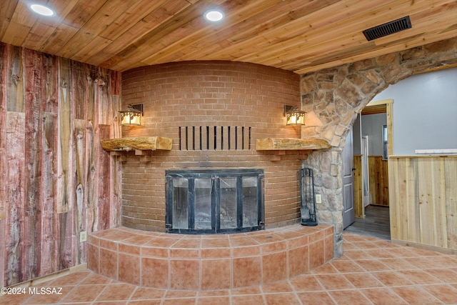 unfurnished living room featuring a stone fireplace, wooden ceiling, and wooden walls