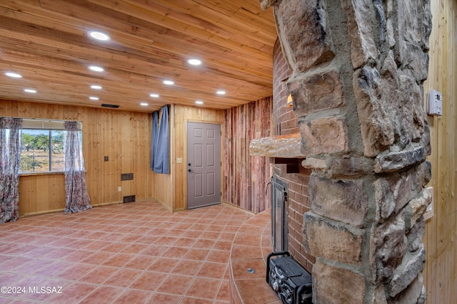 interior space featuring a stone fireplace, wood walls, and wood ceiling