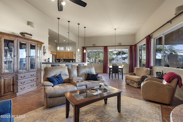 living room with ceiling fan, light tile patterned floors, and a high ceiling