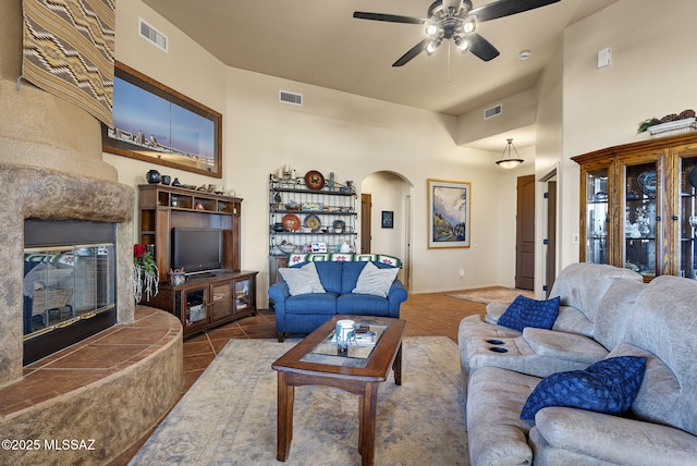 living room featuring tile patterned flooring, ceiling fan, and a tiled fireplace