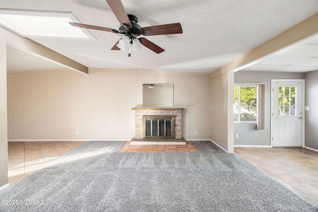 unfurnished living room with ceiling fan, brick wall, carpet floors, and beam ceiling