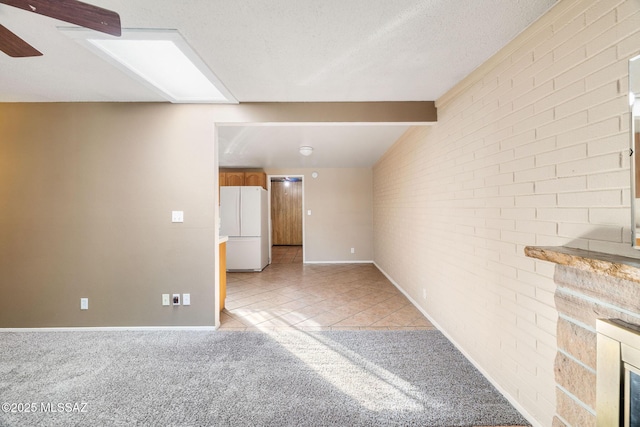 carpeted empty room featuring ceiling fan, brick wall, a textured ceiling, and beam ceiling