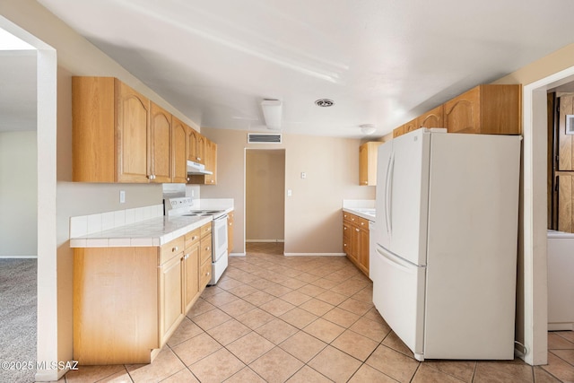 kitchen featuring light brown cabinets, tile countertops, light tile patterned floors, and white appliances