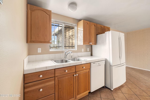 kitchen with sink, white appliances, brick wall, tile countertops, and light tile patterned flooring