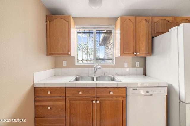 kitchen with white dishwasher, sink, and tile counters