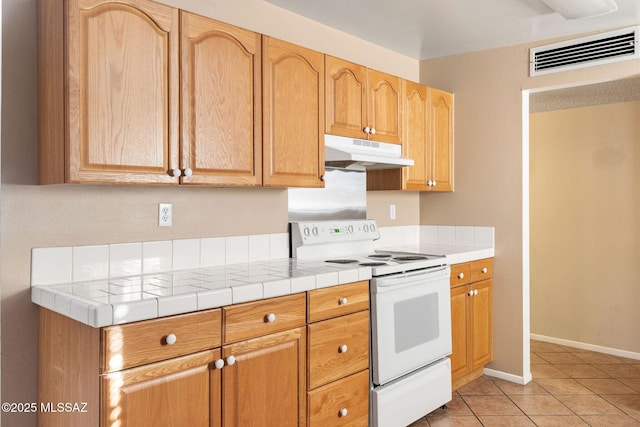 kitchen featuring tile counters, electric range, and light tile patterned floors