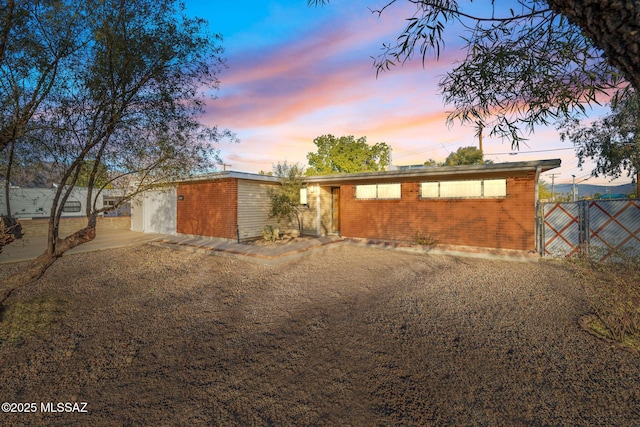 view of front of property with a garage, brick siding, fence, and driveway