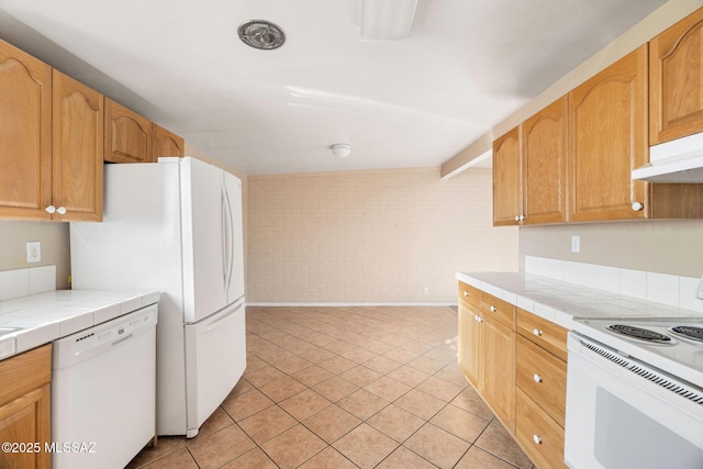 kitchen featuring light tile patterned flooring, white appliances, brick wall, and tile counters