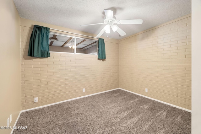 spare room with ceiling fan, brick wall, carpet flooring, and a textured ceiling