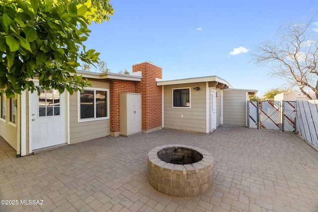 rear view of property with a patio area and an outdoor fire pit