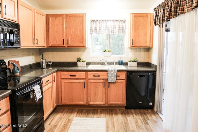 kitchen featuring black appliances, tasteful backsplash, a sink, and light wood-style flooring