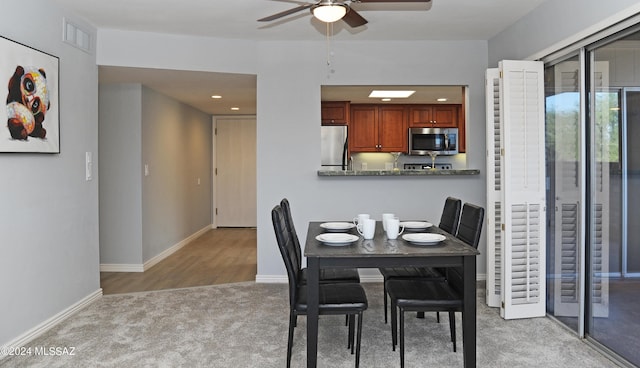 carpeted dining area with ceiling fan