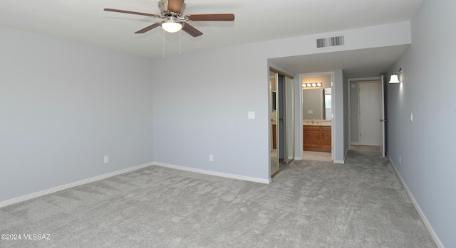 unfurnished bedroom with ensuite bath, light colored carpet, ceiling fan, and sink