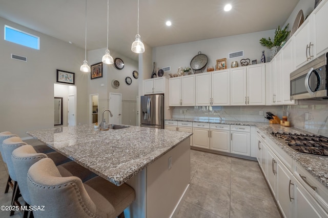 kitchen with sink, stainless steel appliances, tasteful backsplash, a kitchen island with sink, and white cabinets