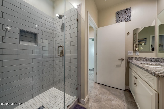 bathroom featuring baseboards, vanity, tile patterned flooring, and a stall shower