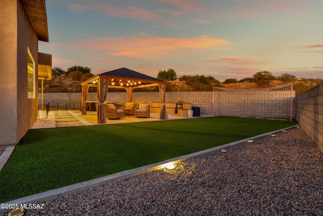 yard at dusk featuring a fenced backyard, a gazebo, a patio area, and an outdoor hangout area