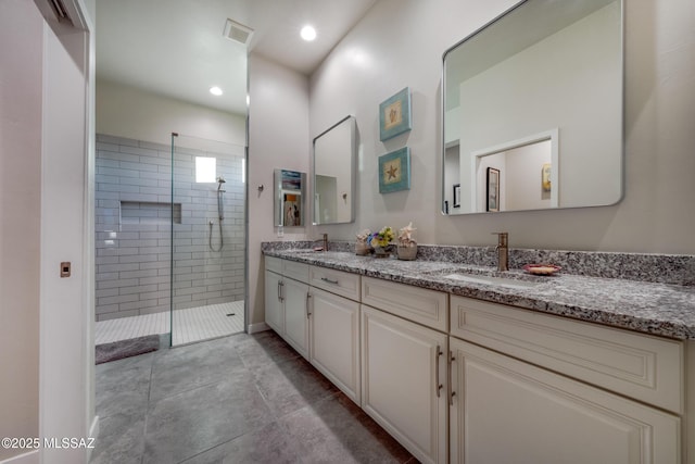 bathroom with a tile shower and vanity