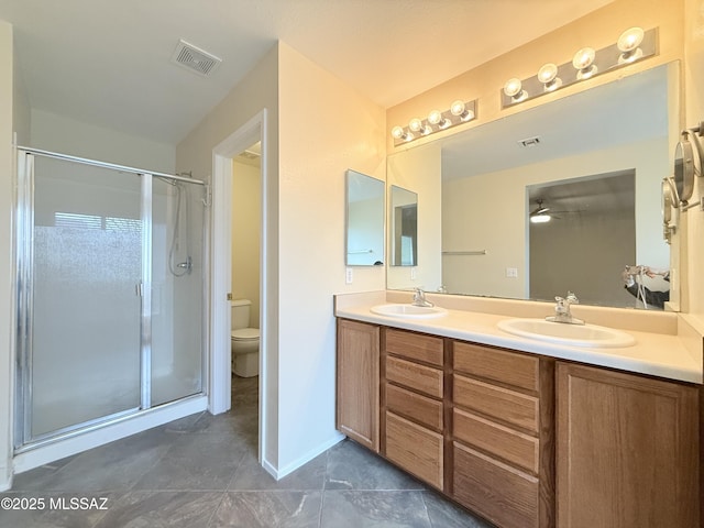 bathroom featuring vanity, toilet, ceiling fan, and a shower with shower door