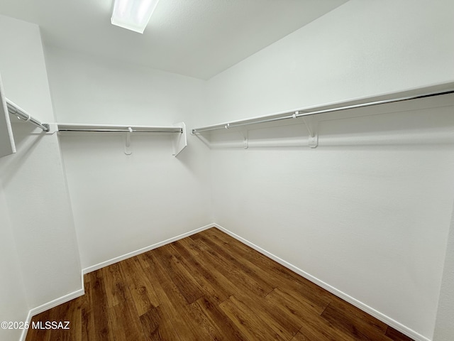 walk in closet with dark wood-type flooring