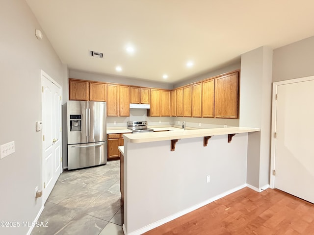 kitchen featuring sink, a kitchen bar, kitchen peninsula, and stainless steel appliances