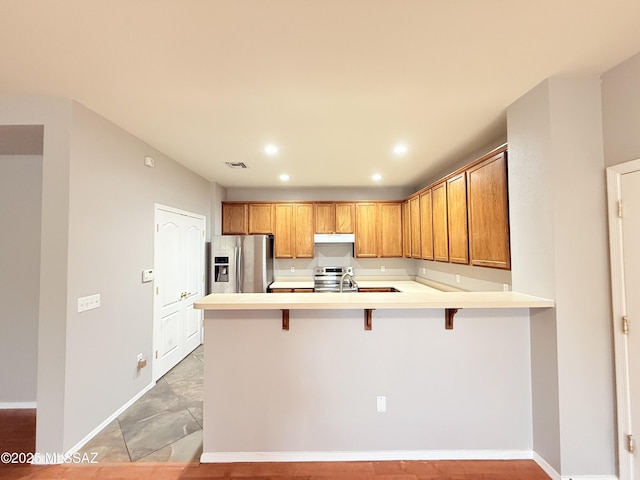 kitchen featuring a kitchen breakfast bar, sink, kitchen peninsula, and stainless steel appliances