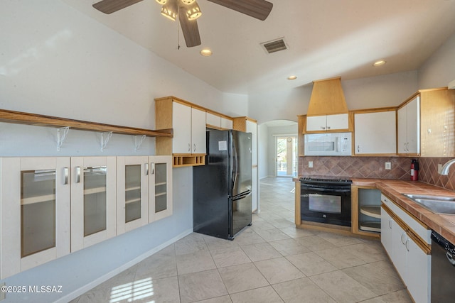 kitchen with black appliances, arched walkways, white cabinets, and a sink