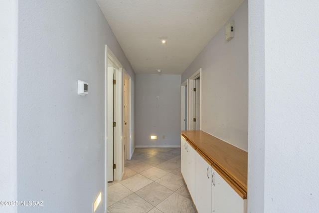 hallway featuring light tile patterned floors and baseboards