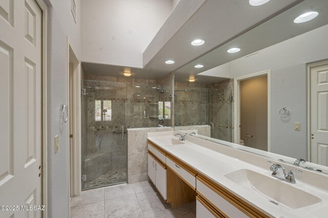 bathroom featuring double vanity, a stall shower, a sink, and toilet