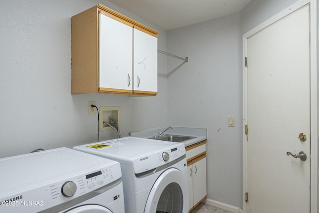 clothes washing area with cabinet space, a sink, and washing machine and clothes dryer