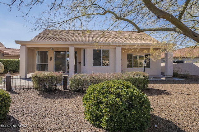 view of front of property with a tile roof, fence, a ceiling fan, and stucco siding