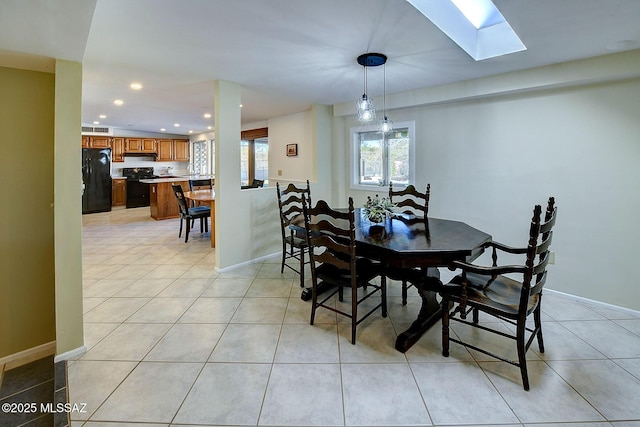 dining room with a skylight and light tile patterned floors