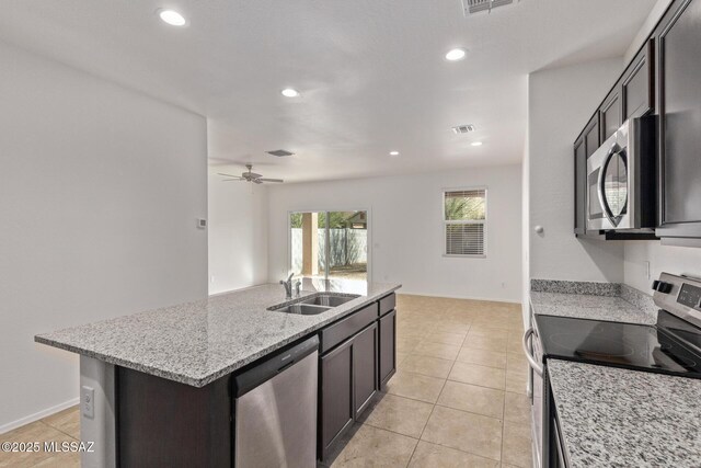 kitchen featuring light tile patterned flooring, appliances with stainless steel finishes, a center island with sink, and sink