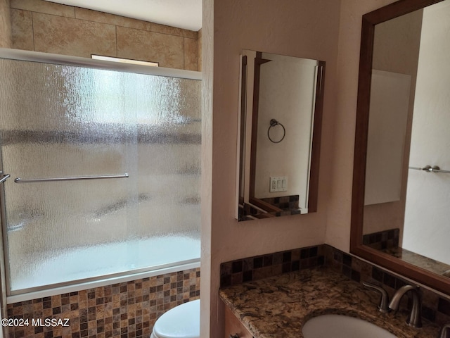 bathroom featuring vanity, toilet, a shower with door, and a wealth of natural light