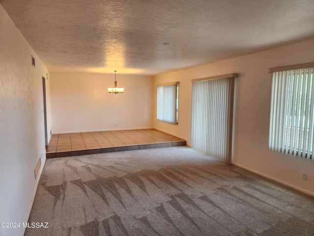 spare room featuring a healthy amount of sunlight, carpet floors, and an inviting chandelier