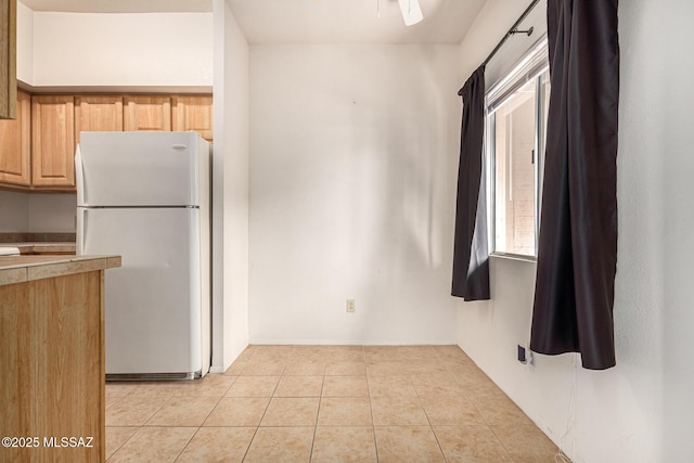 kitchen featuring ceiling fan, white refrigerator, light tile patterned floors, and light brown cabinets