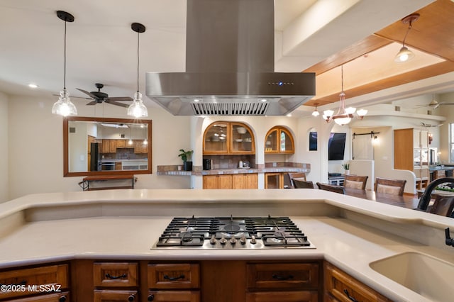 kitchen with pendant lighting, stainless steel gas cooktop, island range hood, and a barn door