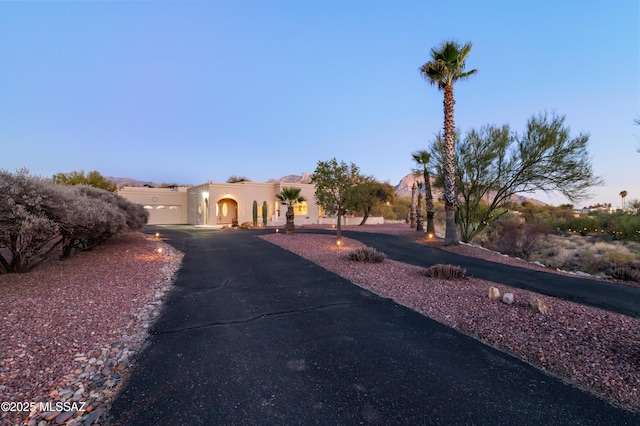 pueblo revival-style home featuring driveway and stucco siding