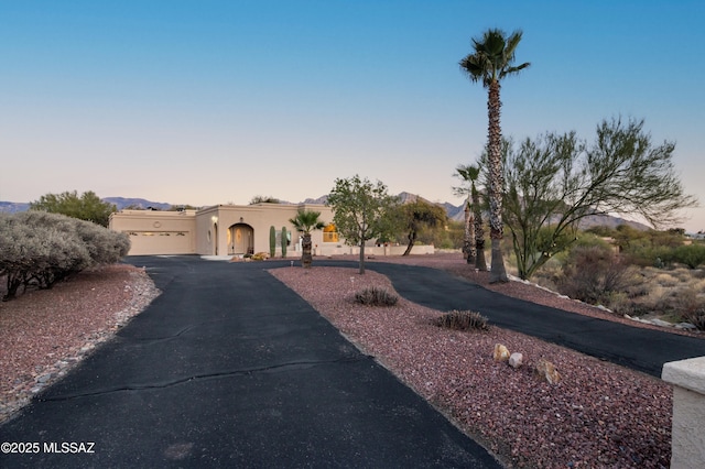 view of front of house featuring a garage, a mountain view, aphalt driveway, and stucco siding