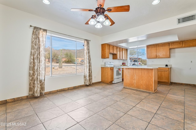 kitchen with ceiling fan, white electric range oven, and a center island