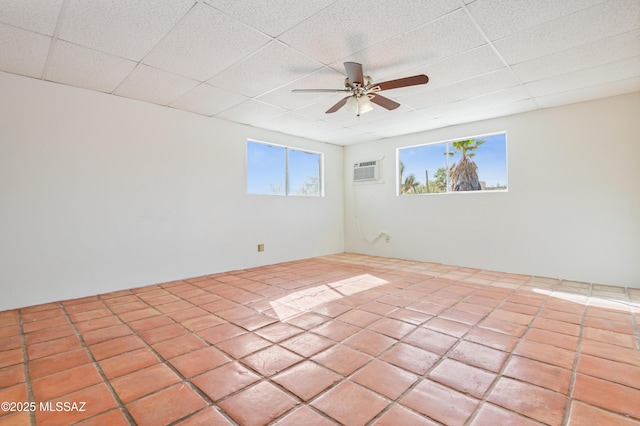 empty room with a wall mounted air conditioner, a drop ceiling, and ceiling fan