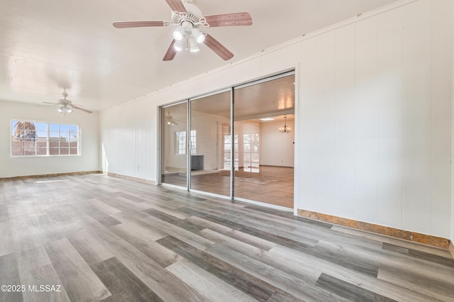 spare room with hardwood / wood-style floors and ceiling fan with notable chandelier