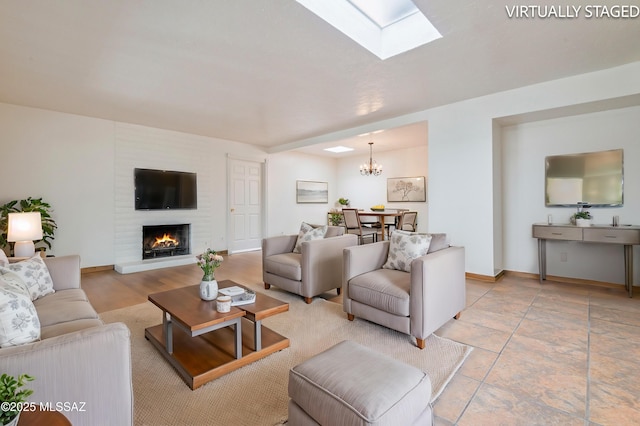 living room with a brick fireplace, a notable chandelier, and a skylight