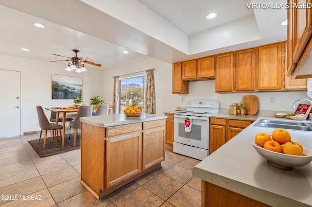 kitchen featuring sink, ceiling fan, electric range, a center island, and a raised ceiling